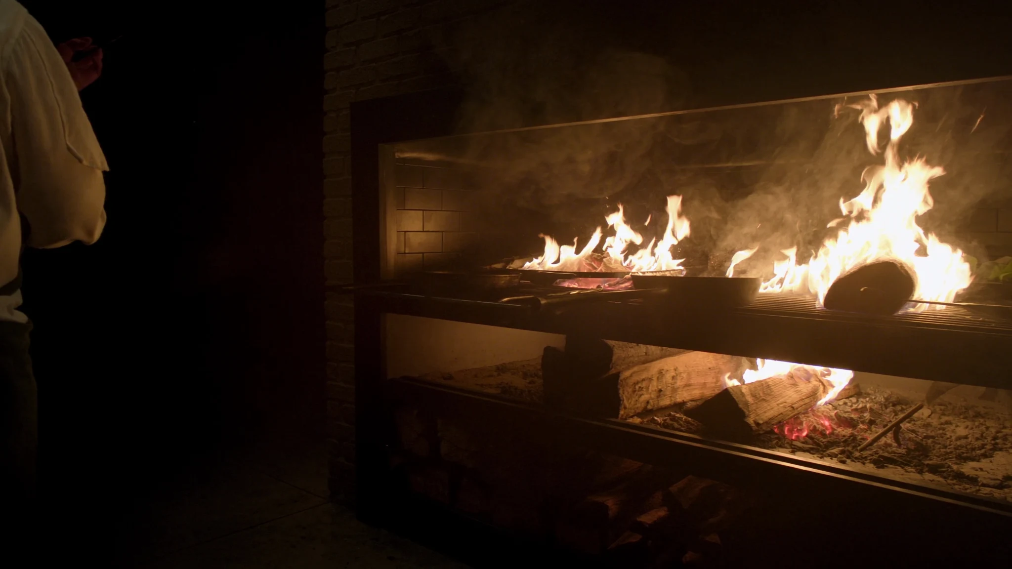 Cooks tending a glowing open-fire grill in the Emberhollow kitchen