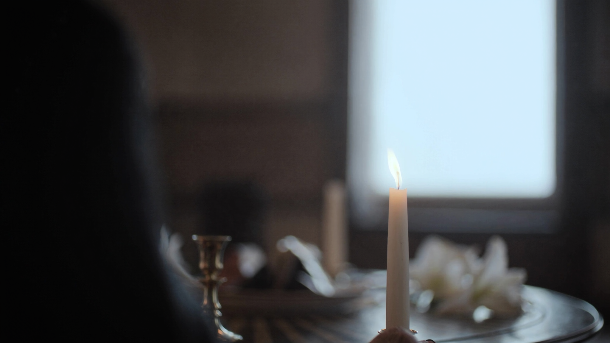 A single lit candle resting on a wooden table in a calm, quiet room