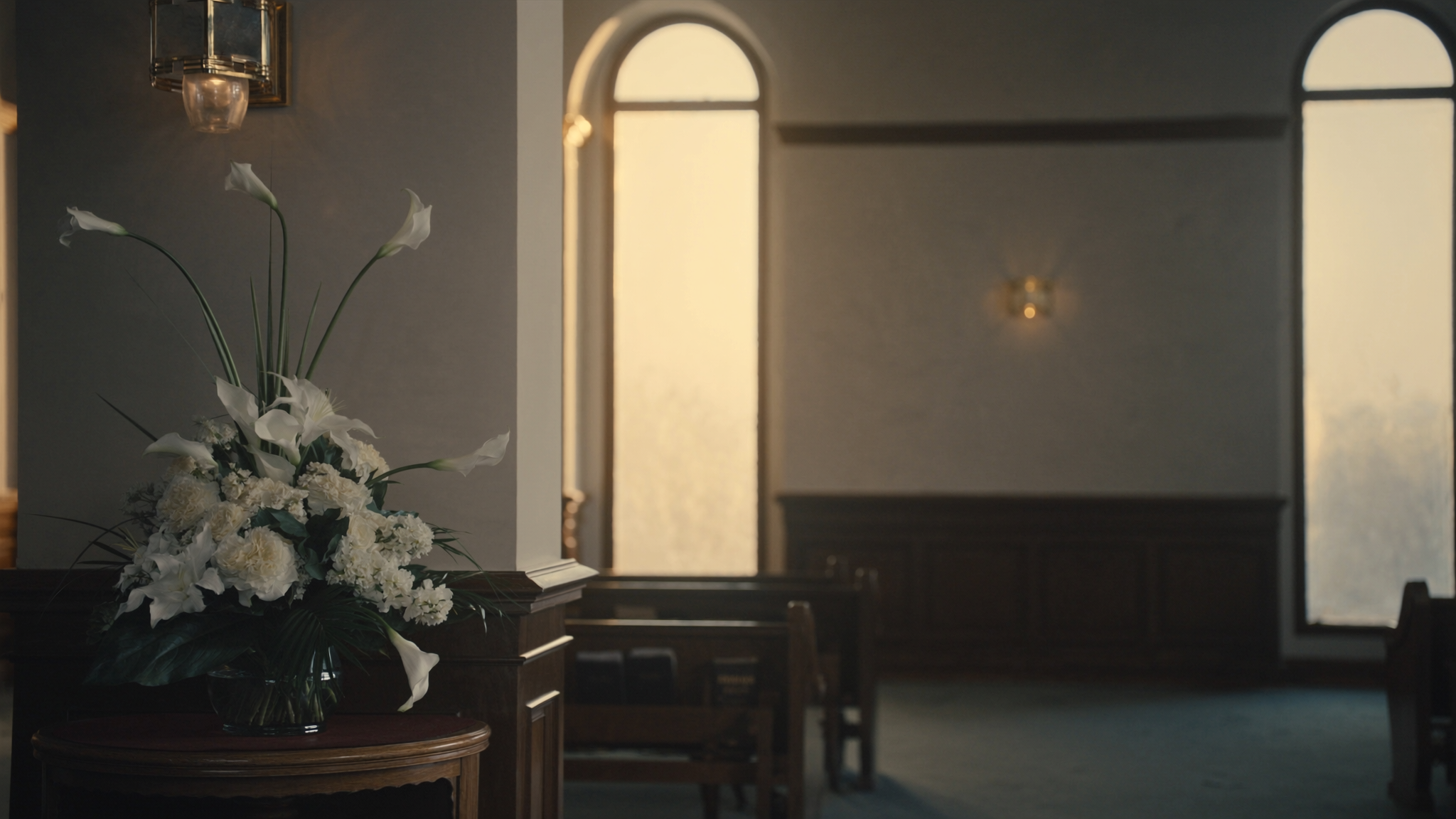 A quiet, softly lit chapel interior with rows of wooden pews and gentle daylight